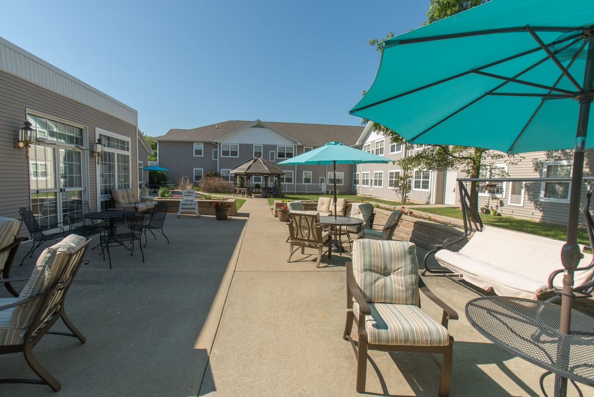 An outdoor patio area with tables, chairs, and umbrellas under a clear blue sky.