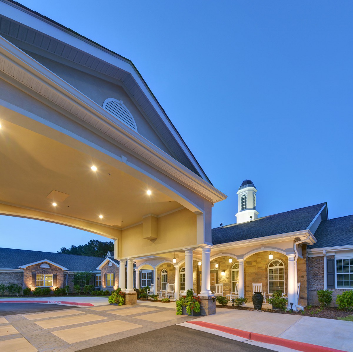 An illuminated building entrance during the evening with a clear sky.
