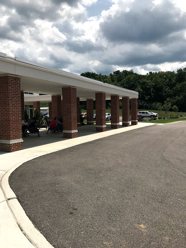 A view of a brick building with a covered entrance, set against a cloudy sky.