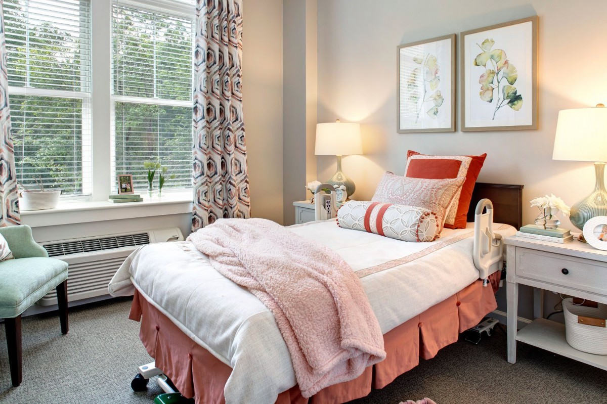 Cozy bedroom with a neatly arranged bed, decorative pillows and a warm ambiance.