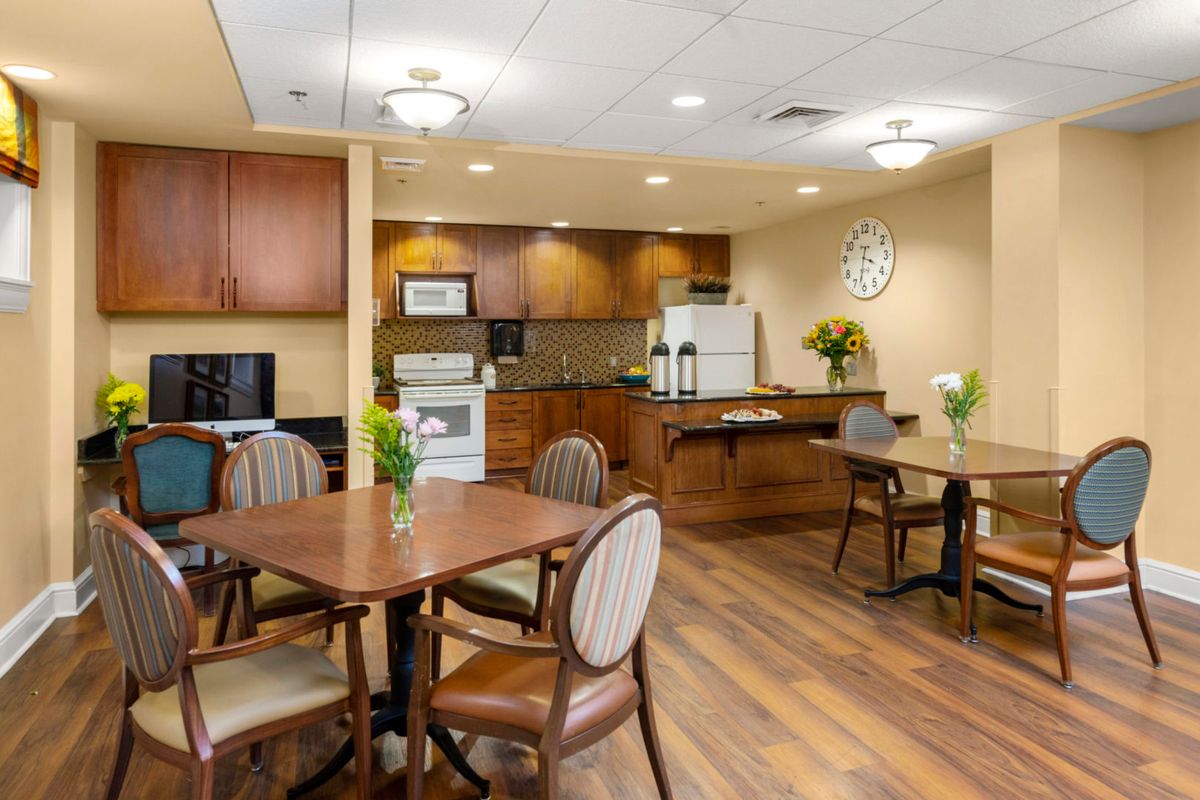 A cozy kitchen and dining area with wooden tables and chairs, featuring modern appliances and warm decor.