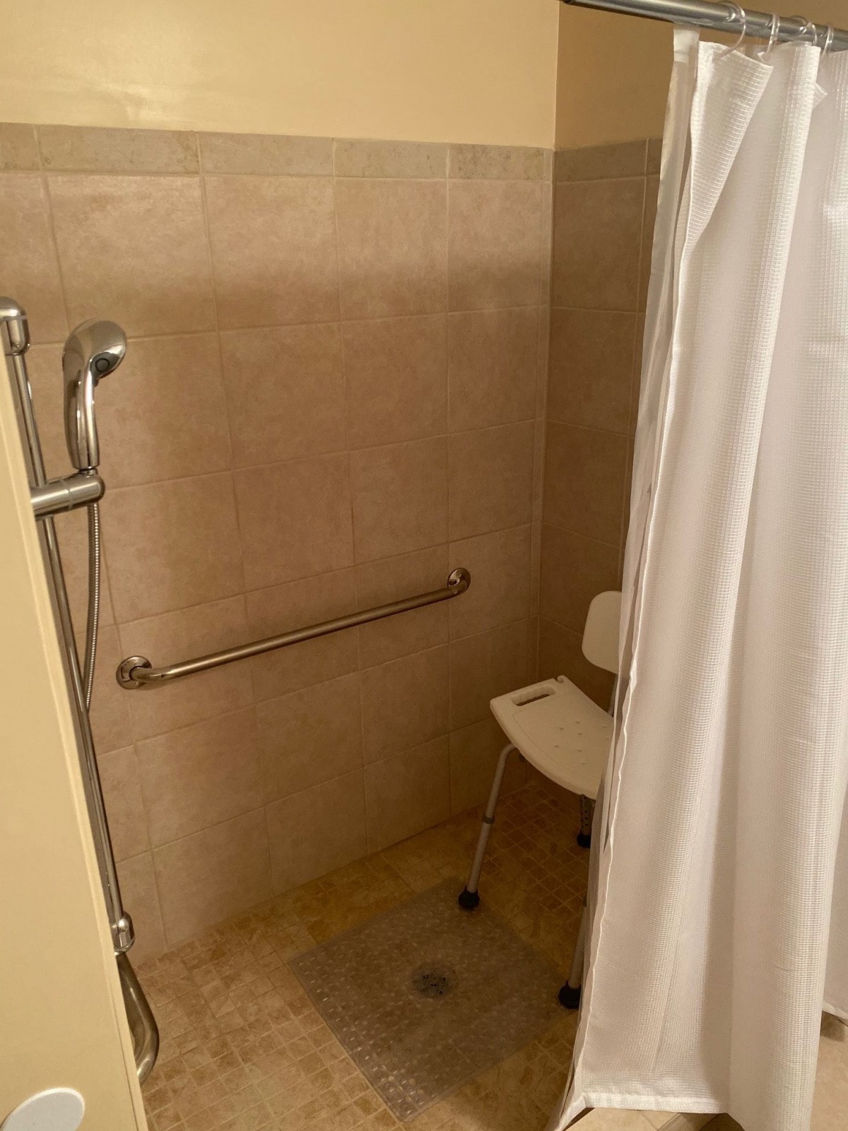 An accessible shower equipped with a shower chair and grab bar.