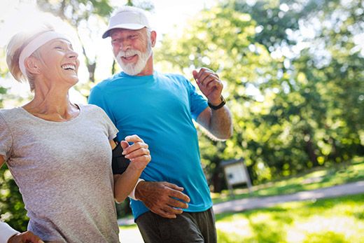 An elderly couple enjoys jogging together in the park, embracing a healthy and active lifestyle.