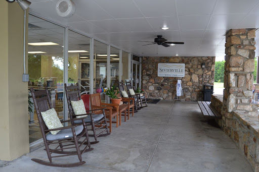 A cozy waiting area featuring rocking chairs, a stone wall, and plenty of natural light.