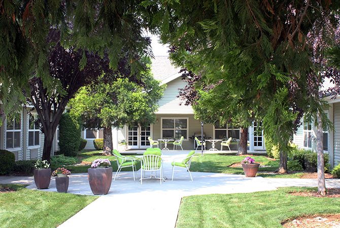 A tranquil garden setting with a house, surrounded by lush trees and a well-maintained lawn.