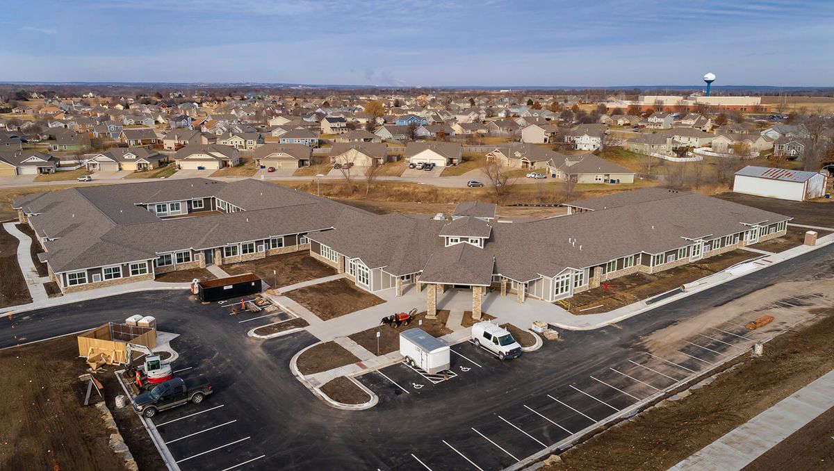 Aerial view of a suburban building complex with a large parking lot and surrounding residential area.