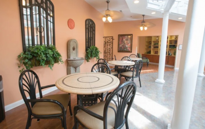 A cozy cafe interior with tables and chairs, decorated with plants and warm lighting.