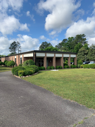 A well-maintained building surrounded by greenery and blue skies.