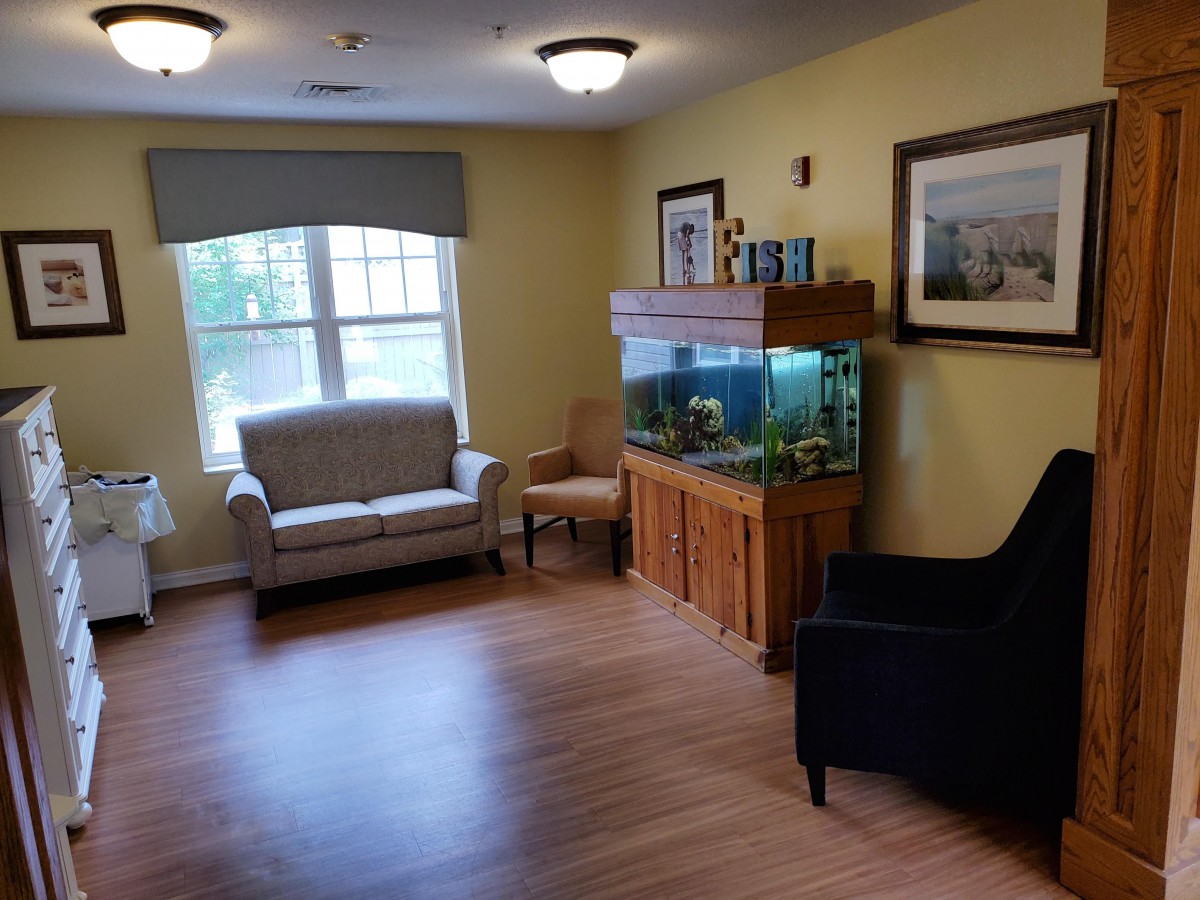 A cozy living room with seating and an aquarium by the window.