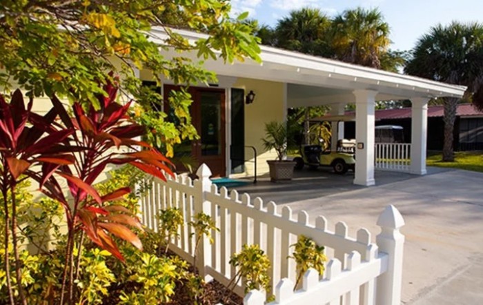 A charming house with a white picket fence and a sunny front yard.