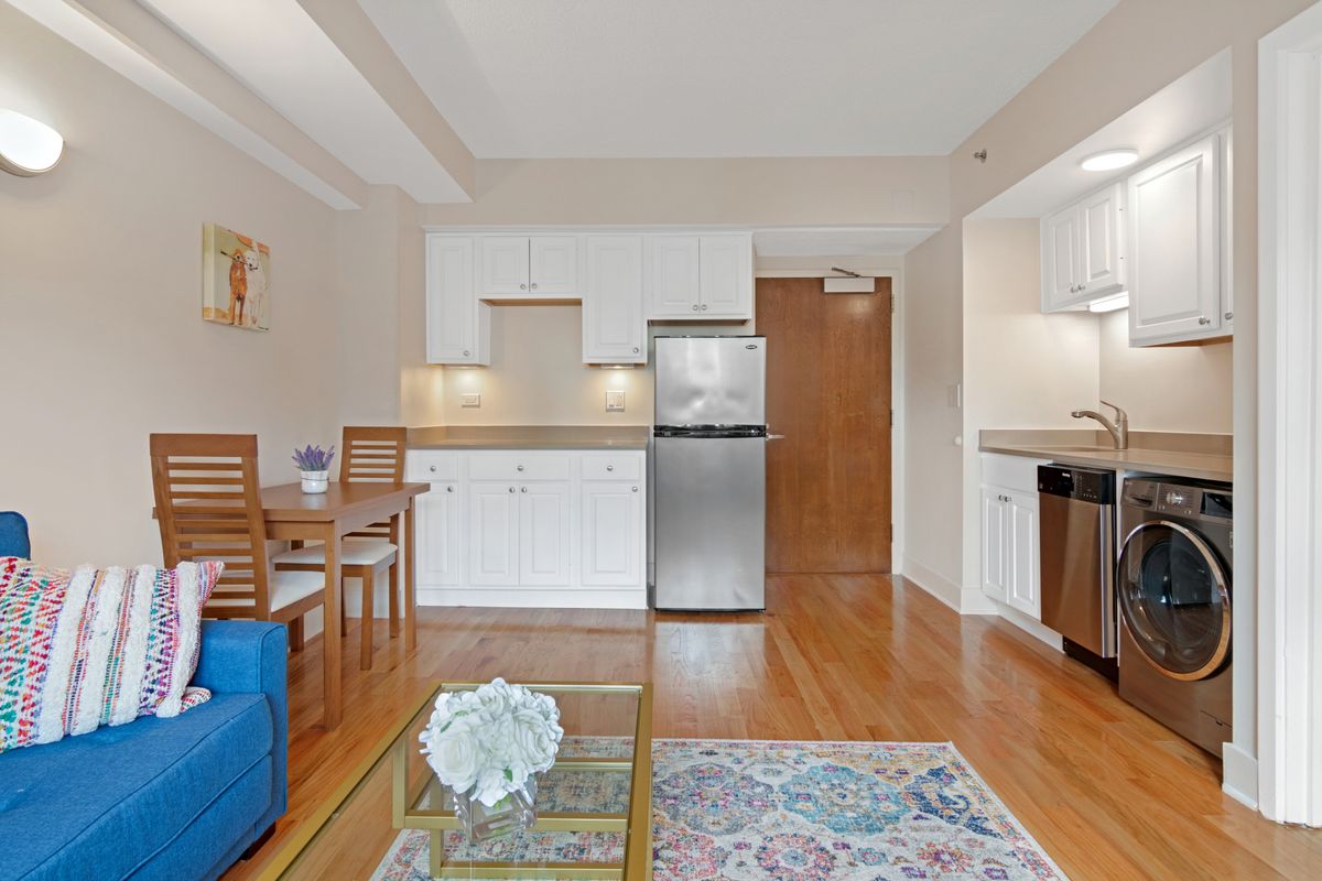 A modern apartment with an open kitchen and living area featuring wooden floors.