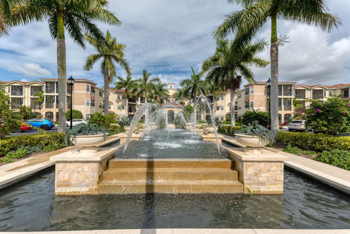 A scenic view of a fountain surrounded by palm trees in a residential area.