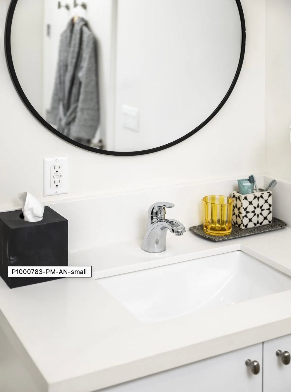 A modern bathroom sink area with a round mirror and neatly arranged toiletries.