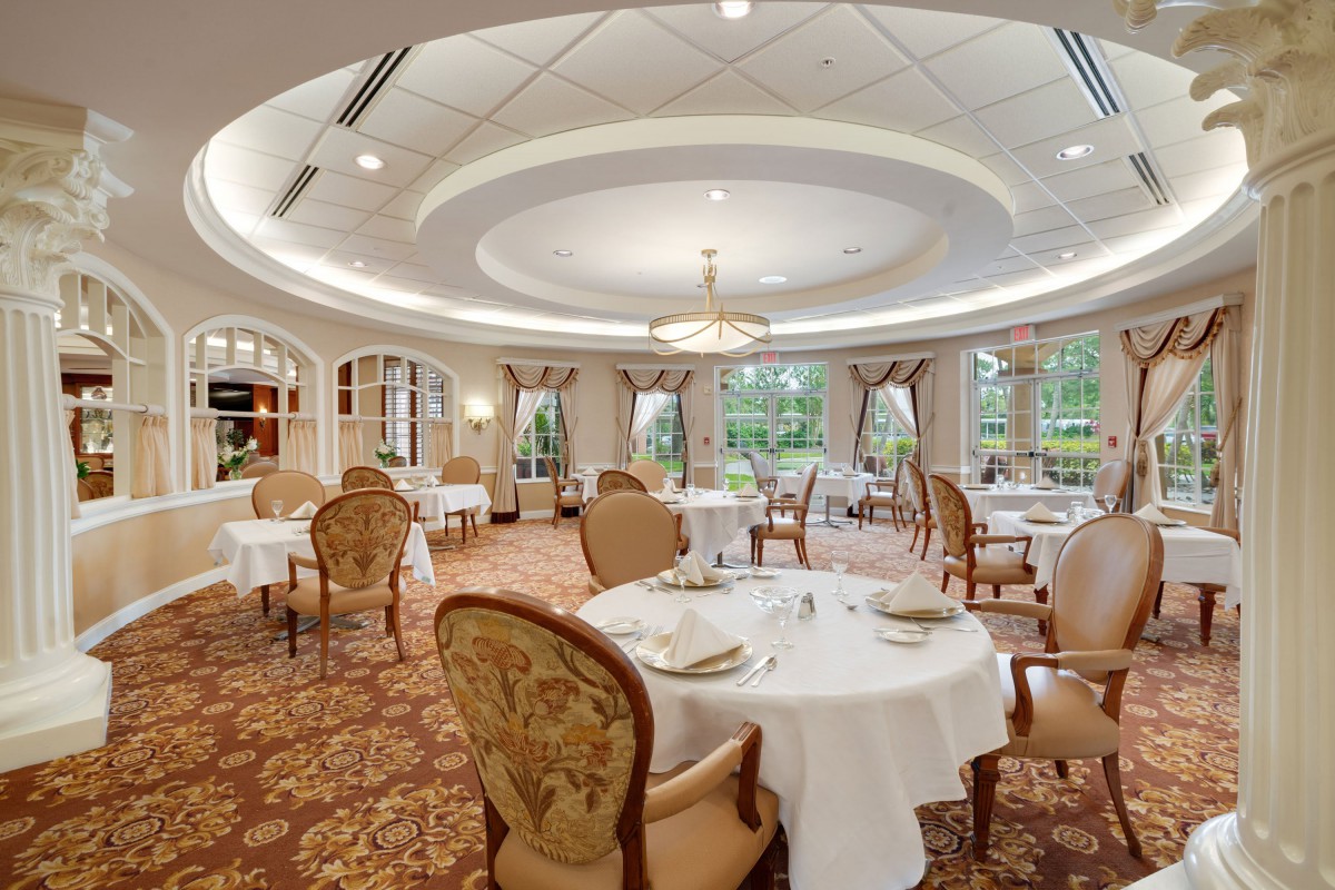 A luxurious and spacious dining room with elegant decor and round tables set for guests.