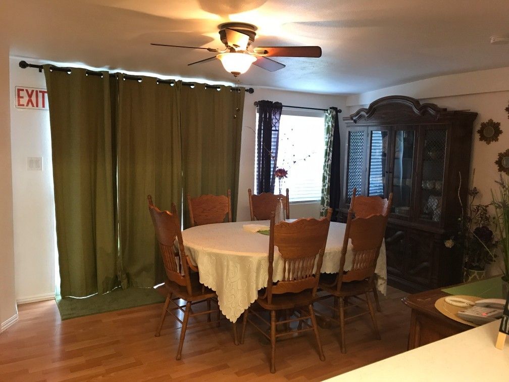 A cozy dining room with a round table, surrounded by wooden chairs, and a china cabinet in the corner.