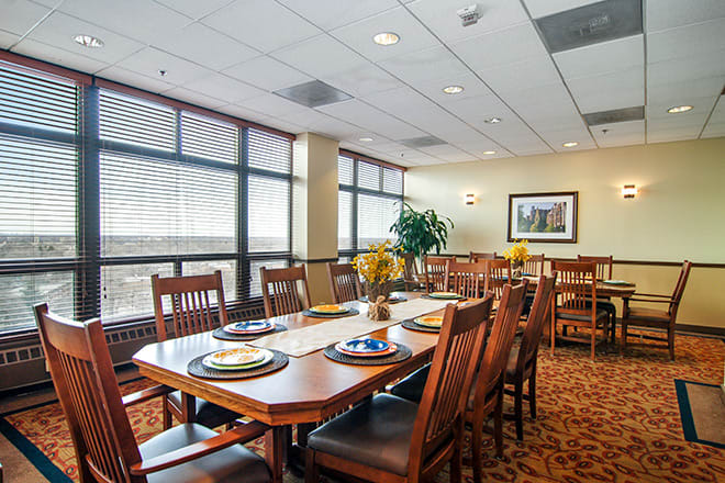 A spacious dining room with a large table, surrounded by wooden chairs and decorated with modern furnishings.