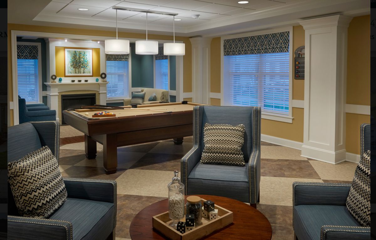 A cozy living room featuring comfortable seating and a pool table, accented with modern decor.