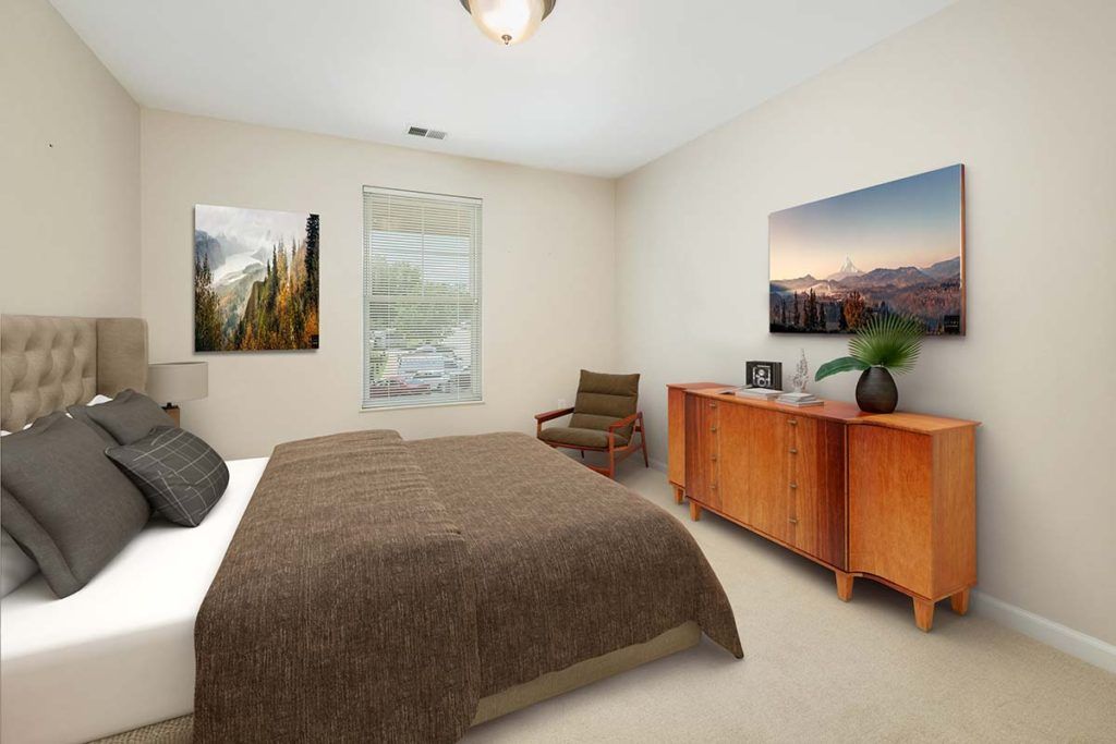 A cozy bedroom featuring a bed with a brown blanket, wooden dresser, artwork on the walls, and a window with natural light.