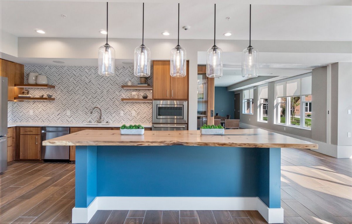 A modern kitchen with a vibrant blue island and pendant lighting.