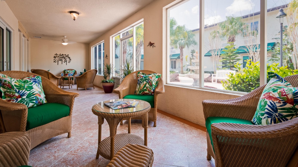 A cozy indoor seating area with wicker furniture and large windows providing ample natural light.