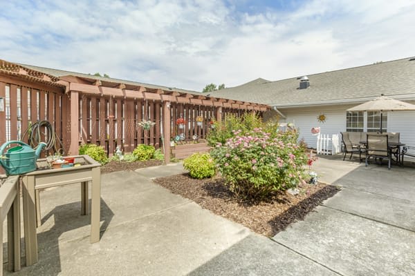 A well-maintained backyard garden with a patio area and various plants.