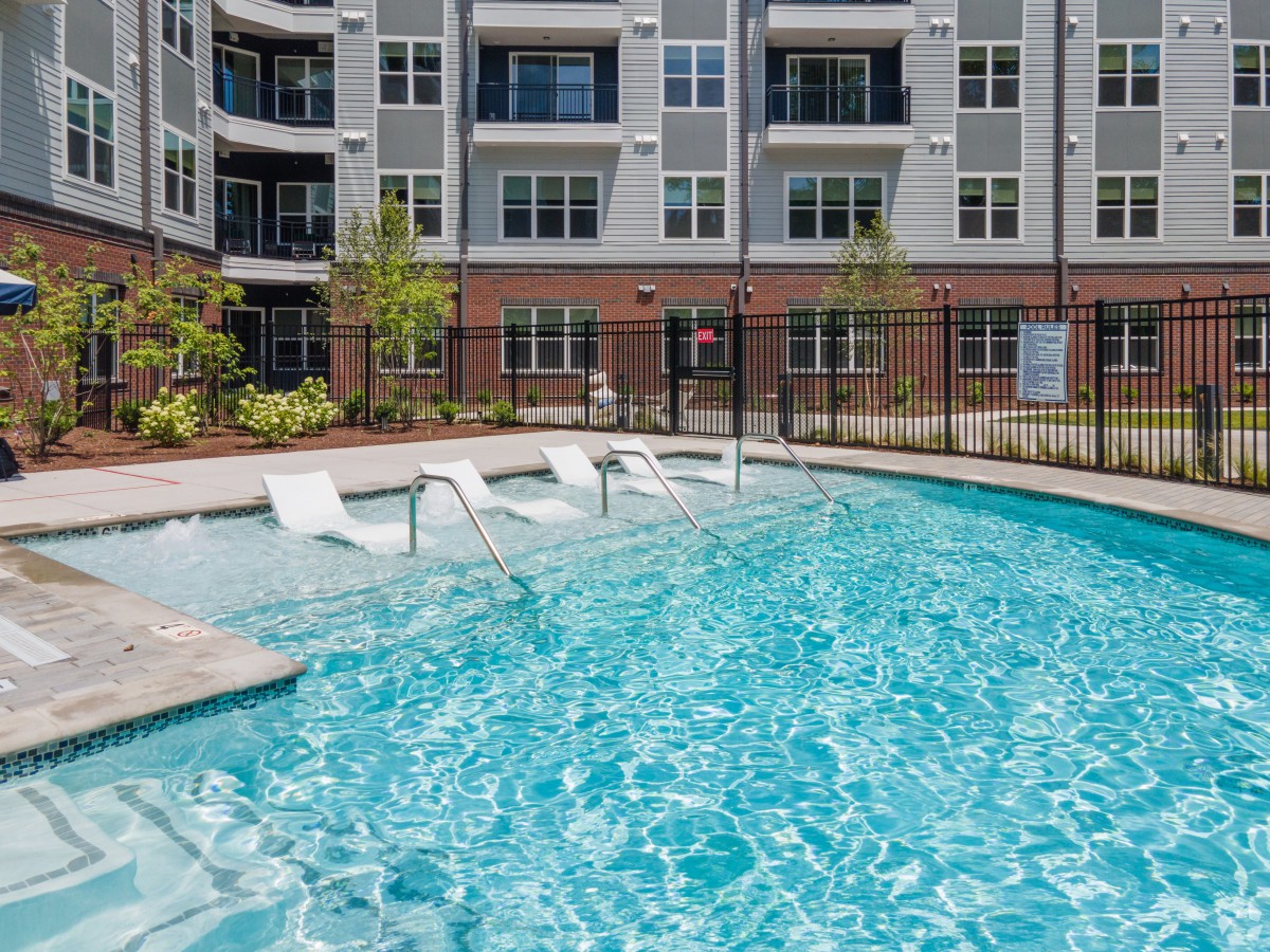 An outdoor swimming pool located within an apartment complex.