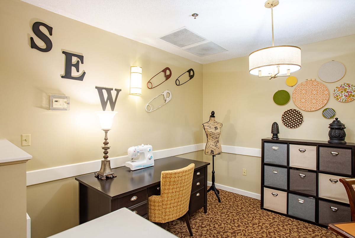 A cozy sewing room with a desk, sewing machine, mannequin, and decorative elements like oversized safety pins.