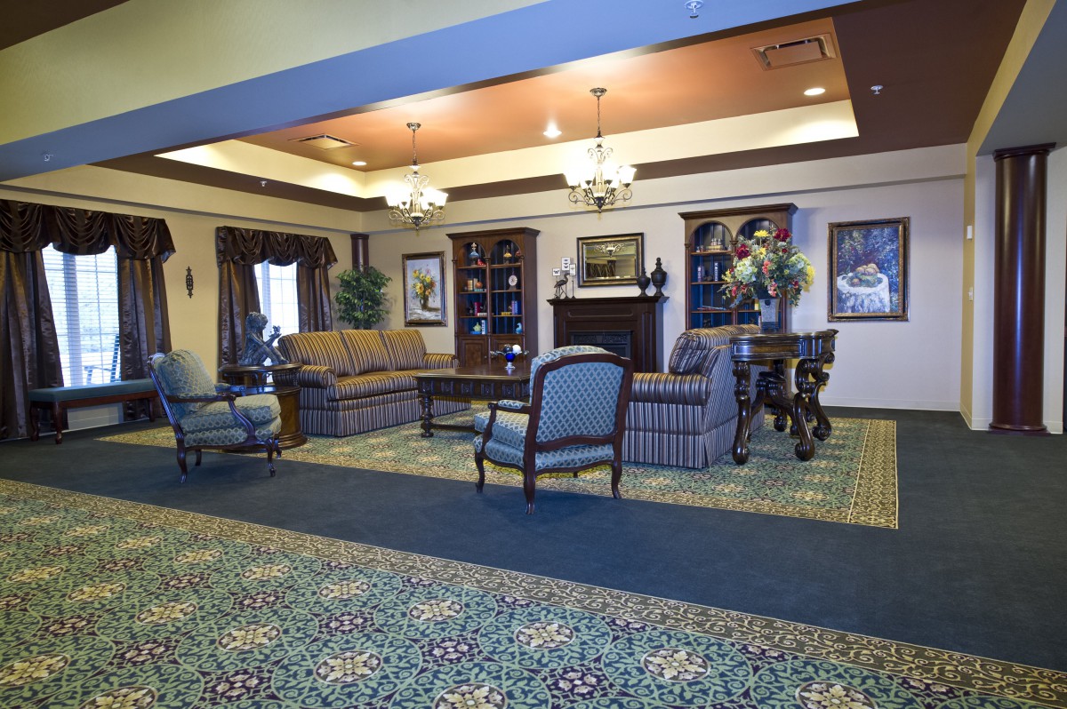 A well-furnished lobby featuring a seating area with sofas and chairs, decorative lighting, and detailed carpeting.