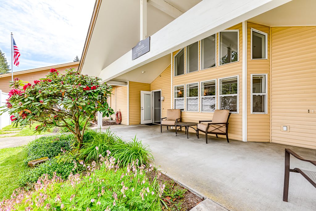 A cozy front porch of a house with seating and a garden area.