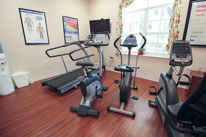 A small fitness room equipped with a treadmill, stationary bike, and an elliptical machine.