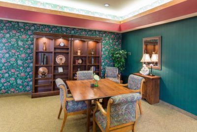 A cozy meeting room with wooden furniture, decorative bookshelves, and an indoor plant.