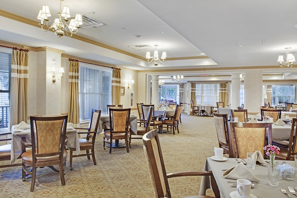 An elegant dining room with neatly arranged tables and chairs, adorned with classic lighting fixtures.