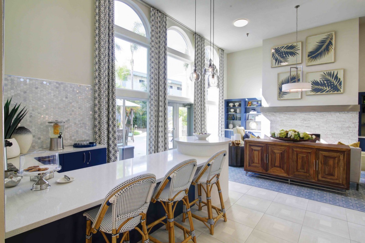 A modern kitchen with a bright and airy feel, featuring a sleek kitchen island, bar stools, and large arched windows.