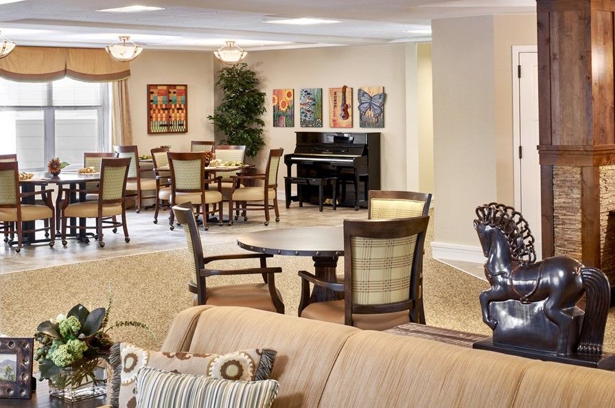 A spacious, well-decorated dining and seating area with elegant furniture, a piano, and colorful artwork on the walls.