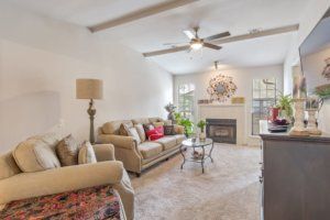 A cozy living room with a beige sofa, fireplace, and ceiling fan.