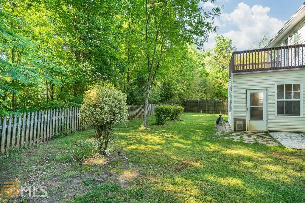 A peaceful backyard with lush greenery and a bordered fence.