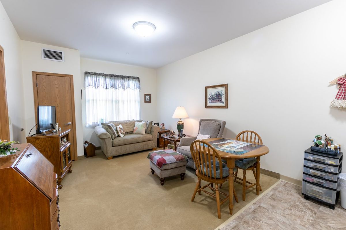 A cozy living room with a sofa, armchairs, and a small dining area.