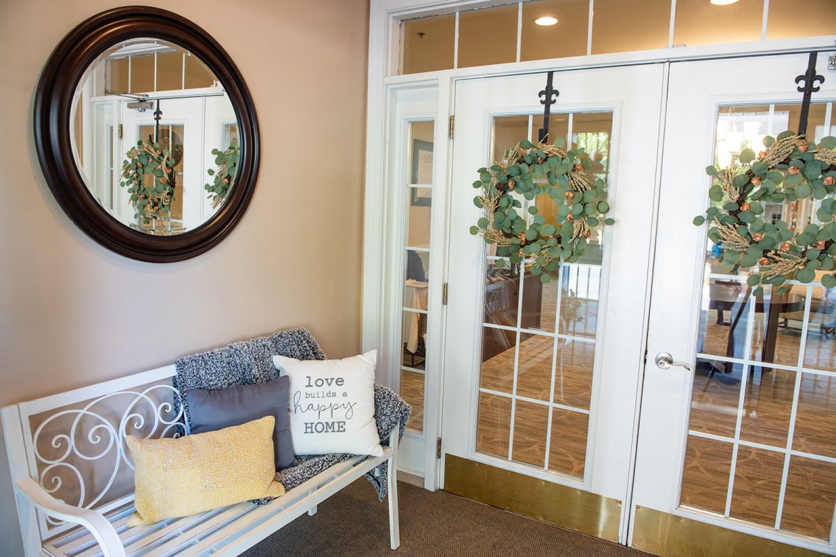 A welcoming entryway with a bench, decorative pillows, and a wreath on the door.