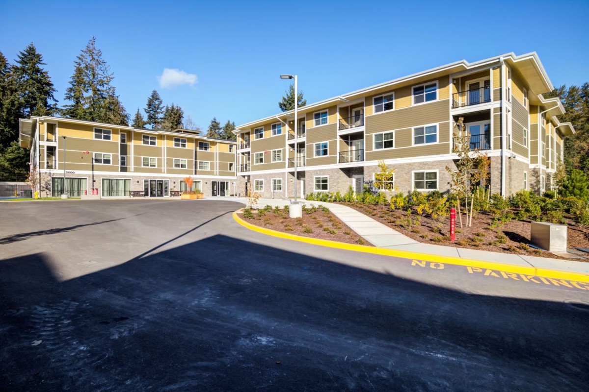 A modern multi-story residential apartment building with landscaped surroundings.