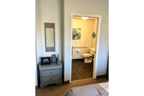 A cozy bedroom with an adjoining bathroom, featuring a nightstand and decor.