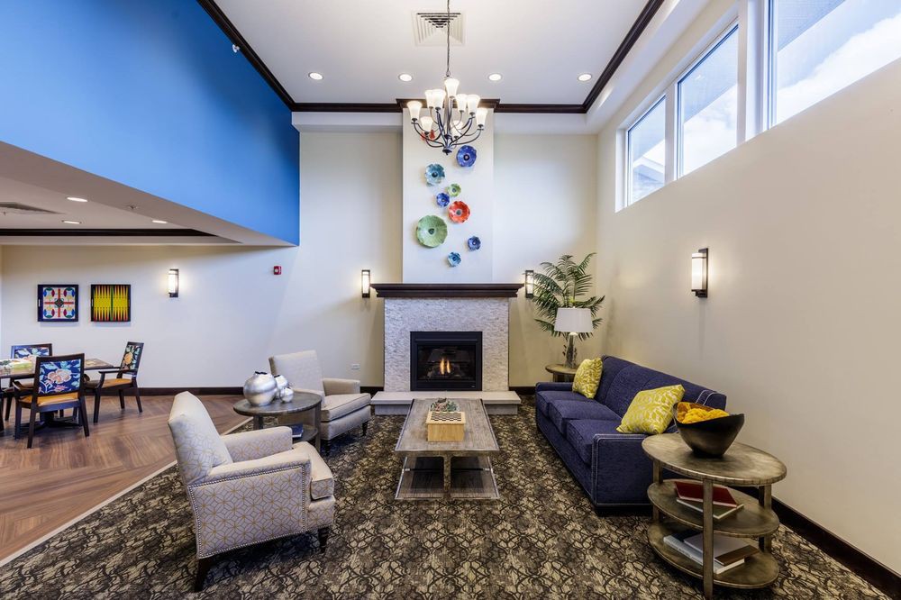 A modern living room featuring a fireplace, elegant chandelier, and colorful wall decor.