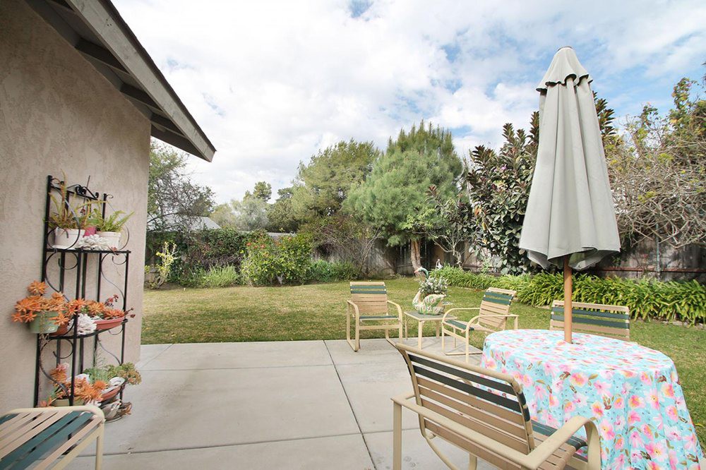 A peaceful backyard patio with outdoor furniture and a garden view.