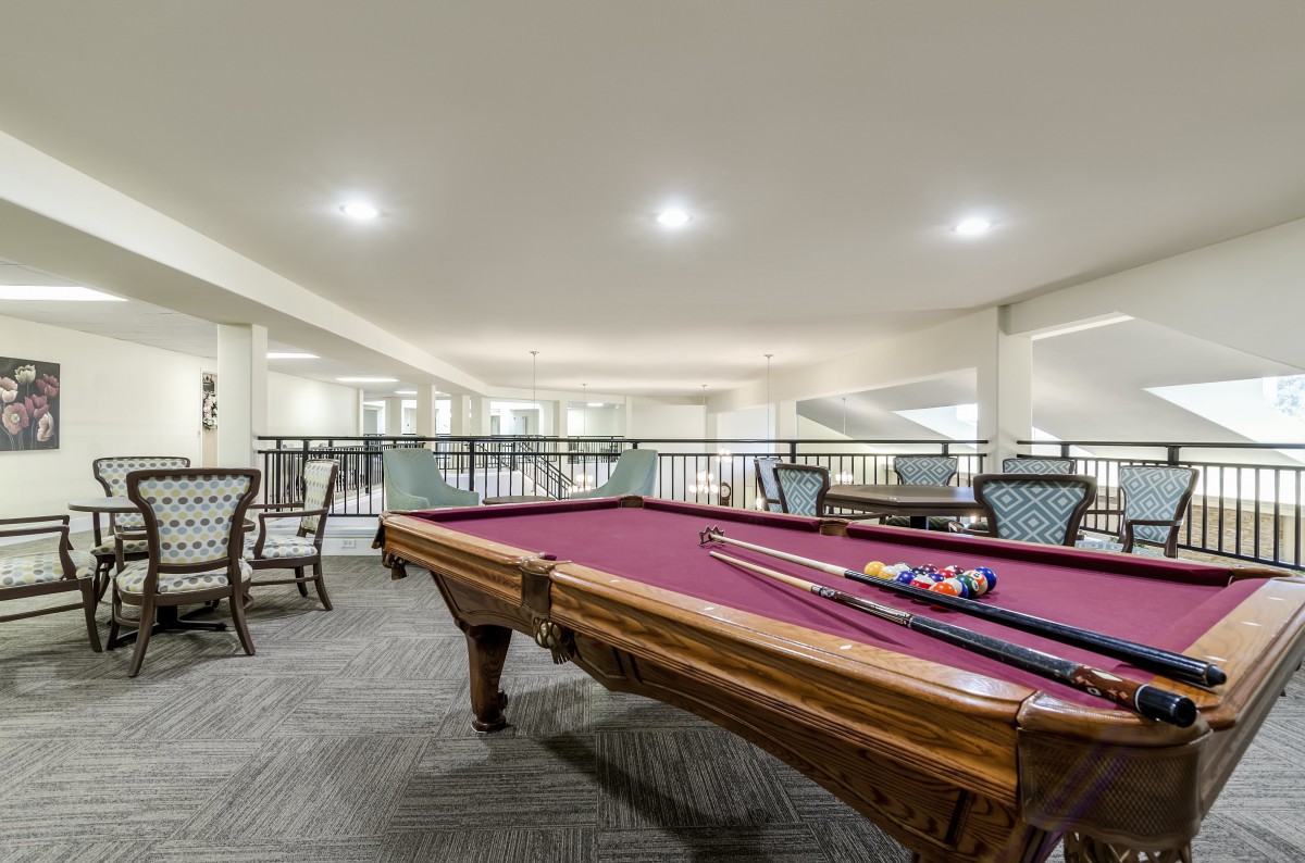 A spacious recreation room featuring a pool table with cue sticks on it.