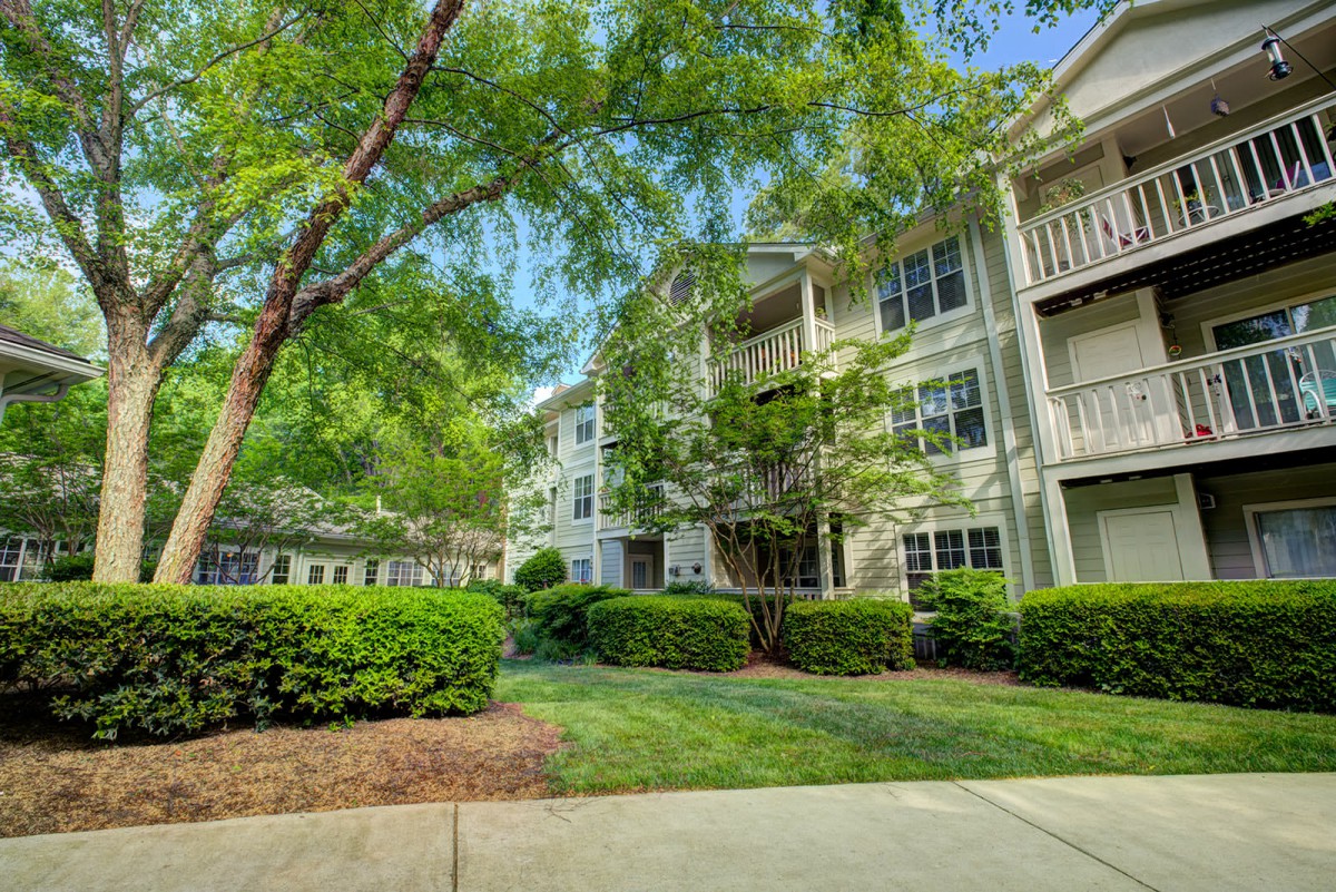 A serene view of a residential apartment complex surrounded by lush trees and well-maintained greenery.