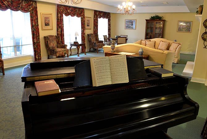 A cozy living room with a piano and comfortable seating arrangements.