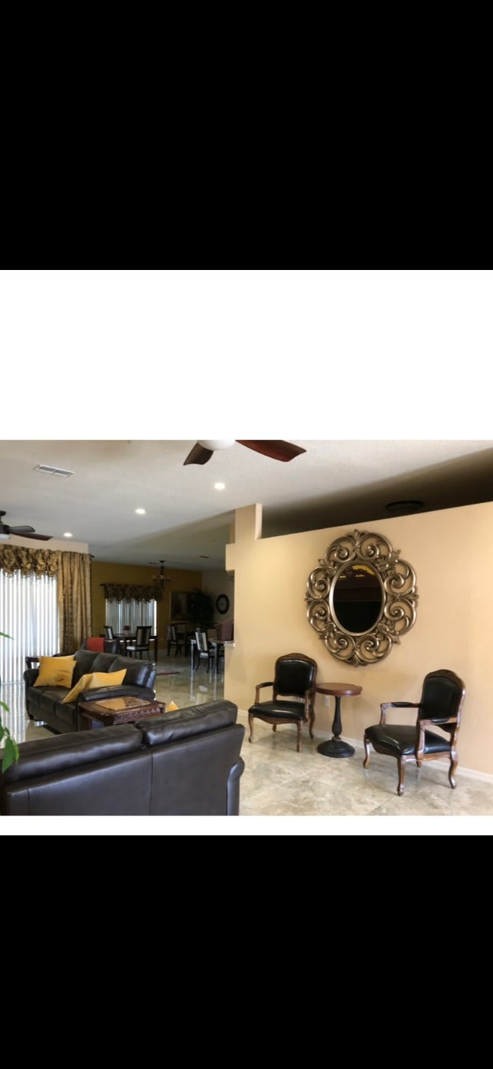 A spacious living room with elegant decor including a large ornate mirror and comfortable seating.