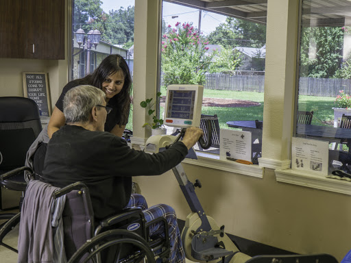A healthcare professional assisting an elderly patient with rehabilitation exercises in a therapy room.