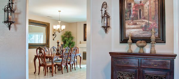 A well-decorated dining room featuring a wooden dining set, chandelier, and artwork on the walls.