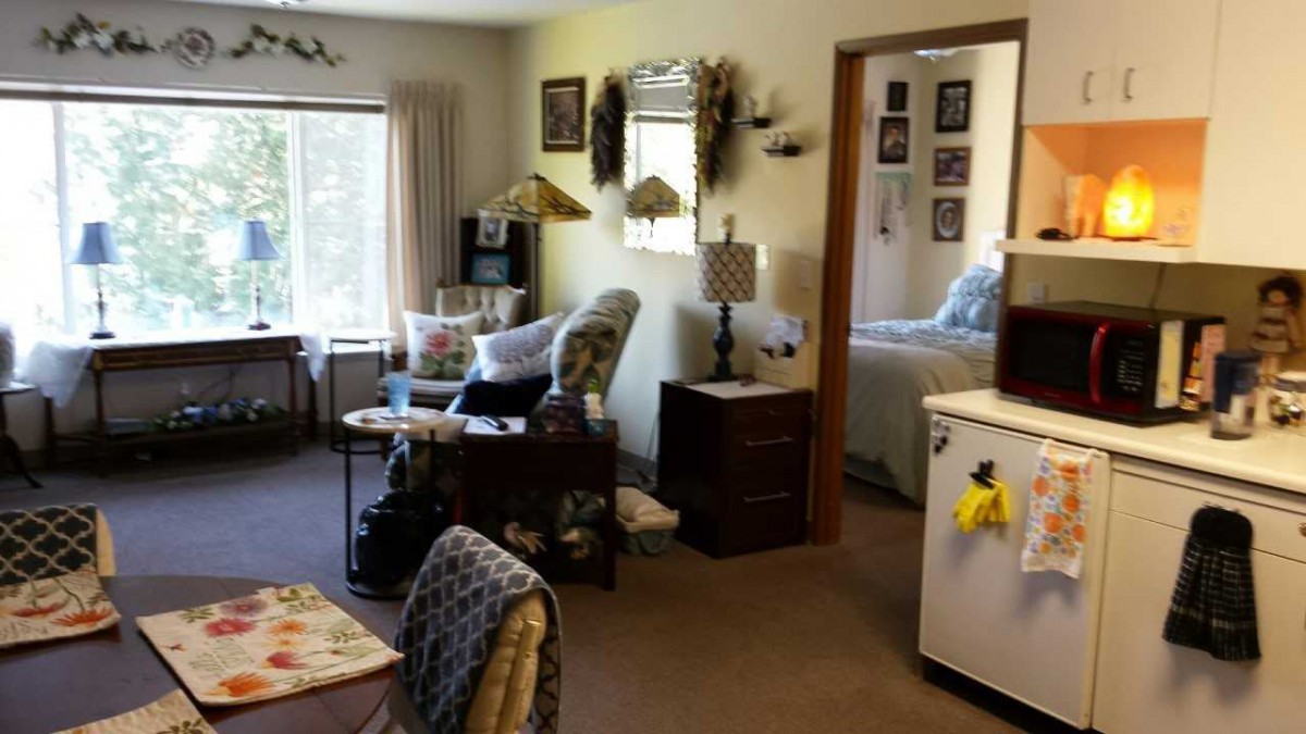 A cozy living room with comfortable seating and a view into the bedroom.