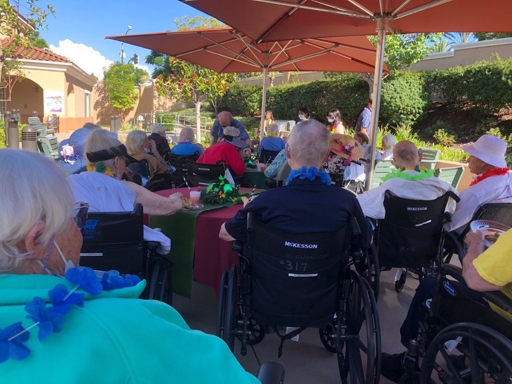 A group of seniors enjoying an outdoor gathering under large umbrellas.